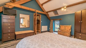Een slaapkamer met een groot bed, een houten dressoir en een kledingkast.