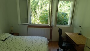 Ein Schlafzimmer mit Bett, Schreibtisch, Stuhl und Heizkörper.