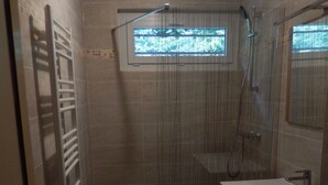 Ein Badezimmer mit Dusche, Waschbecken und Fenster.