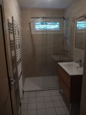 Ein Badezimmer mit Dusche, Waschbecken und Fenster.