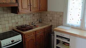 Eine Küche mit Holzausstattung, einem Herd, einem Spülbecken und einem Fenster mit Vorhang.