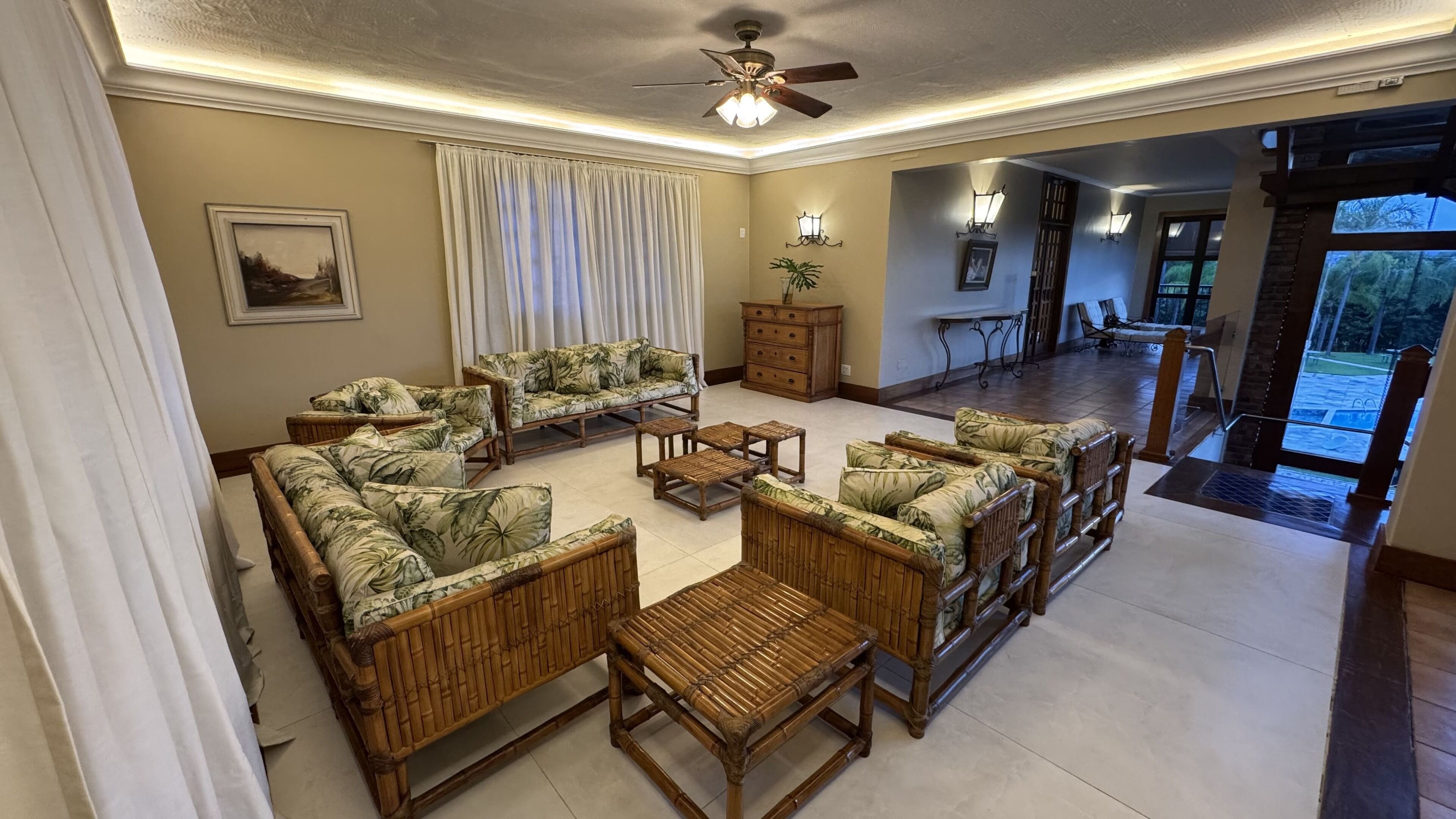 A spacious living room with wicker furniture, a ceiling fan, and a view of the outdoor area.