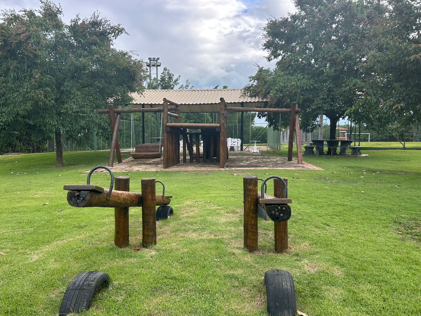 Ein Spielplatz mit einer Holzkonstruktion, Schaukeln und einer Reifen-Schaukel.