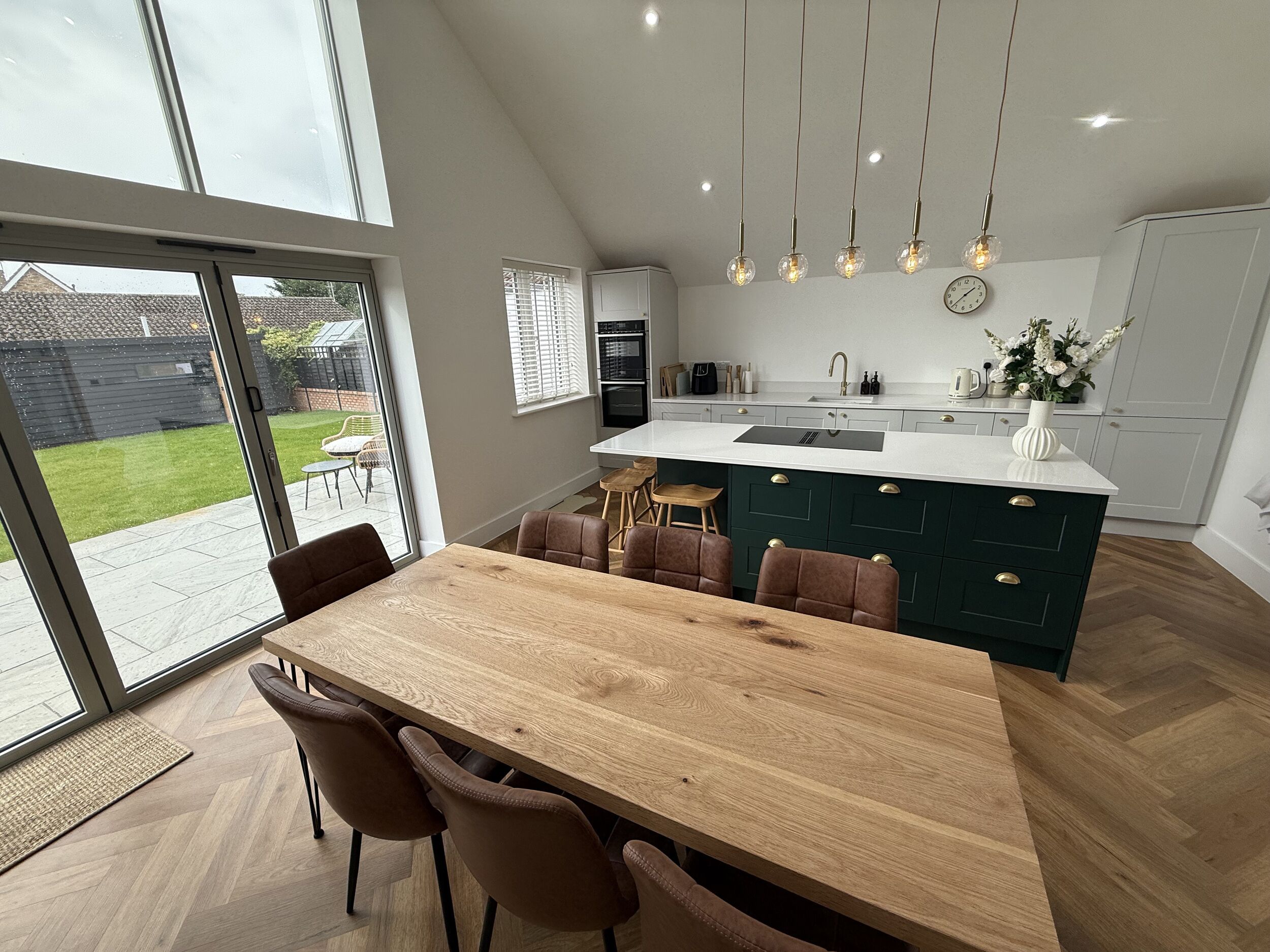 A modern kitchen with a large island, wooden dining table, and chairs.
