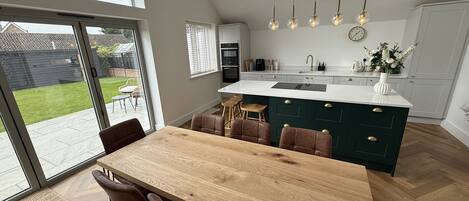 A modern kitchen with a large island, wooden dining table, and chairs.