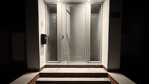 A modern entrance with a double door, a small step leading up, and a light fixture above the door. - Bader House (Ipswich)
