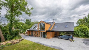 Et moderne hus i to etager med skråtag, store vinduer og en overdækket indkørsel.