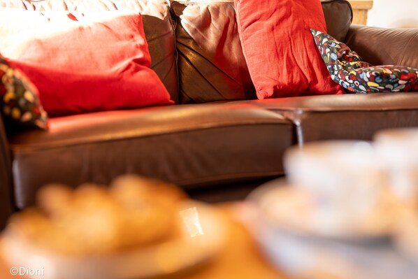 A brown leather sofa with red and multicolored pillows.