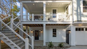 A two-story house with a covered front porch, a staircase, and a garage. - Private Pool + Hot Tub | New 5BR w/ Golf Cart – Steps to Beach (Emerald Isle)