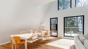Um interior moderno com área de jantar, sofá e janelas amplas com vista para o exterior.