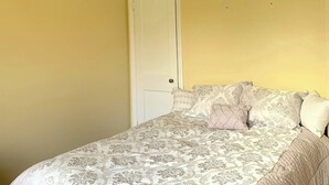 Un dormitorio con cama, puerta y una lámpara en el techo.