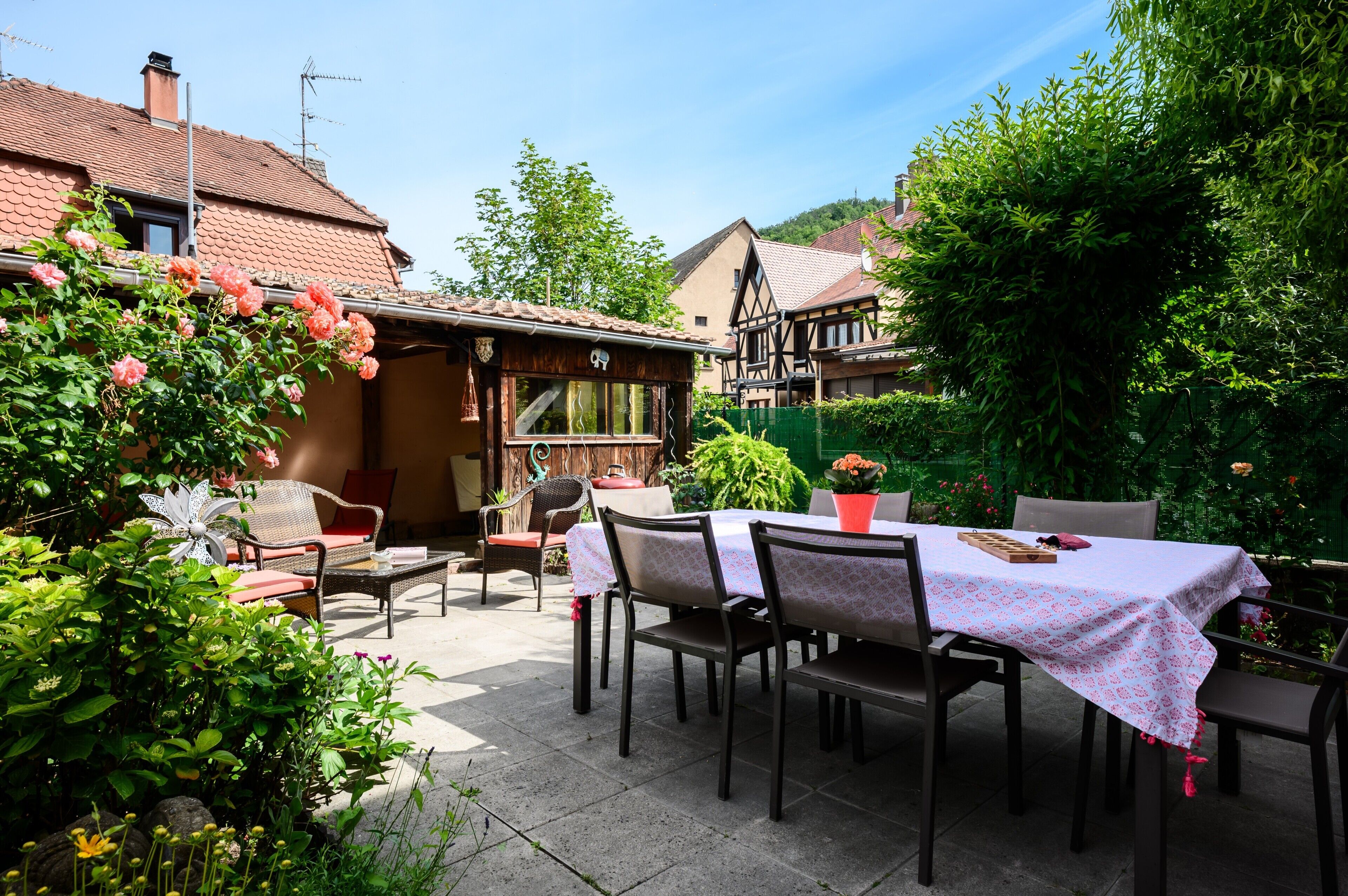 Eine Terrassenfläche mit Esstisch und Stühlen, mit Blick auf traditionelle Häuser im Hintergrund.
