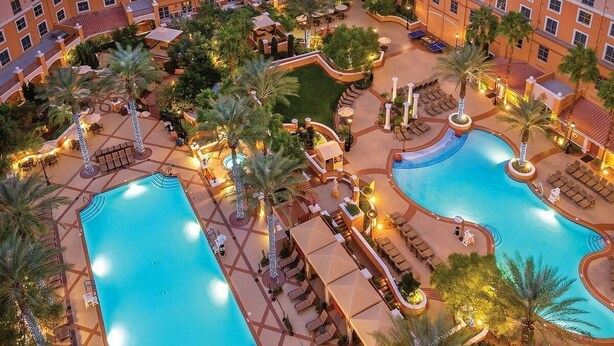 A hotel with multiple swimming pools, outdoor seating areas, and palm trees. - Family Friendly Condo - No Resort fees! (Las Vegas)