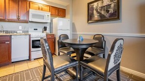 A compact kitchen with wooden cabinets, a microwave, a refrigerator, and a dining area with a round table and four chairs. - Family Friendly Condo - No Resort fees! (Las Vegas)