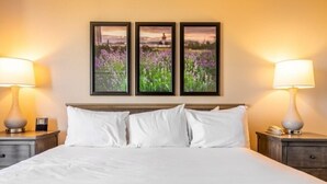 A hotel room with a large bed, two bedside tables, and three framed pictures on the wall. - Family Friendly Condo - No Resort fees! (Las Vegas)