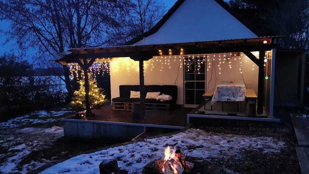 A cozy outdoor seating area with a fire pit, a covered patio, and string lights.