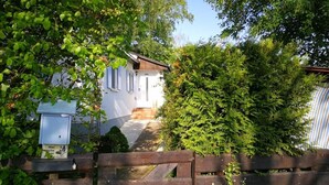 A house with a wooden fence in front, surrounded by lush greenery.