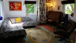 A cozy living room with a zebra-patterned sofa, a massage chair, a bookshelf, and a painting on the wall.