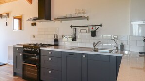 Une cuisine moderne dotée d’un îlot central, de meubles de couleur noire et d’une hotte de cuisson en acier inoxydable.