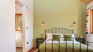 Une chambre à coucher avec un lit, deux tables de chevet, une commode, une fenêtre et une porte.