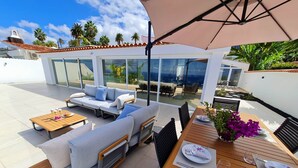 A modern outdoor patio with seating, a dining table, and a large umbrella. - Cachito de Cielo (La Victoria de Acentejo)