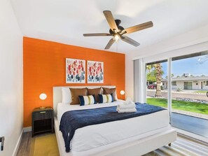 A modern bedroom with a bed, a ceiling fan, artwork on the wall, and a view of the outside. - Dawn-In Old Town-Walk to Entertainment District (Scottsdale)