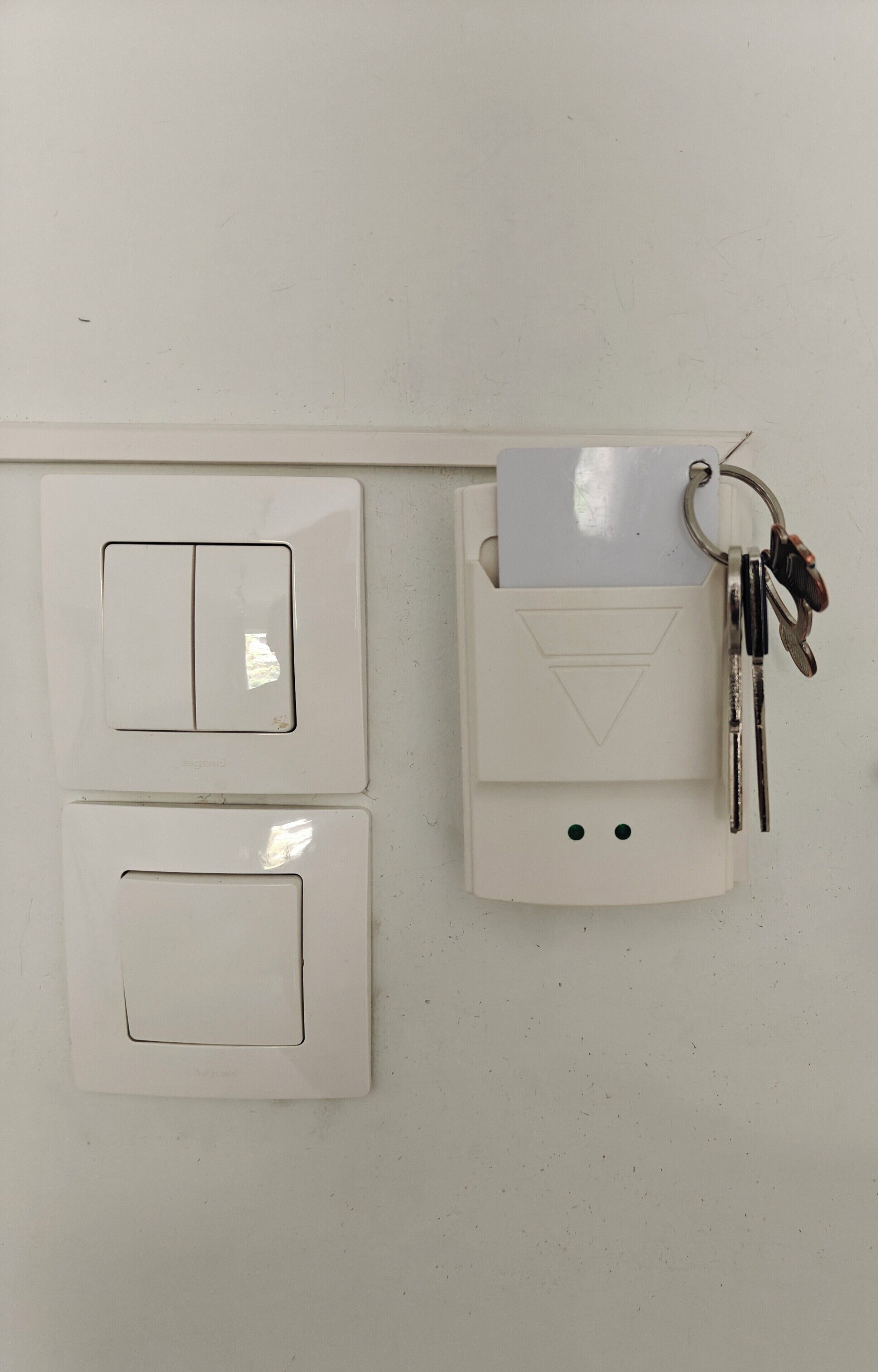 Un tablero de interruptores fijado a la pared con dos interruptores y un llavero con llaves.