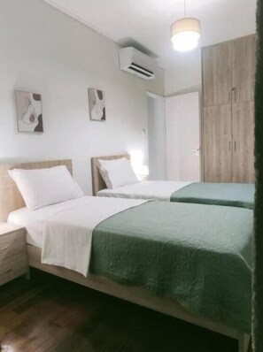 A hotel room with two beds, a wardrobe, and an air conditioning unit. - Marousi Serene Suite (Marousi)