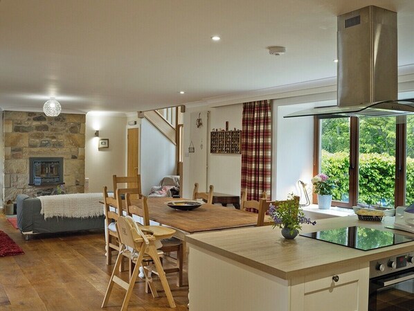 A modern kitchen with a central island, wooden dining table, and built-in appliances. - A large spacious 3 bedroomed house in farmyard courtyard. (Perth)
