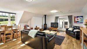 En moderne stue med en sort lædersofa, et træspisebord og et fjernsyn.
