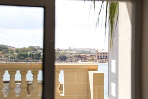 A view from a balcony overlooking a waterfront with buildings and greenery in the background. - Central Sliema Stay | Sea View -Steps to Promenade (Sliema)