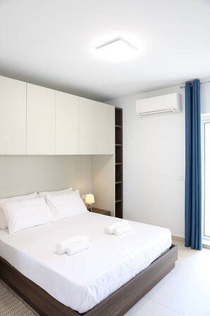 A modern bedroom with a large bed, built-in wardrobe, and an air conditioning unit.