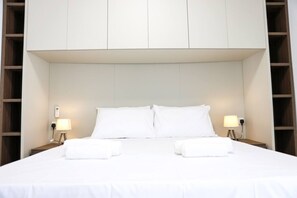 A neatly made bed with white linens, two bedside lamps, and a wall-mounted telephone. - Central Sliema Stay | Sea View -Steps to Promenade (Sliema)