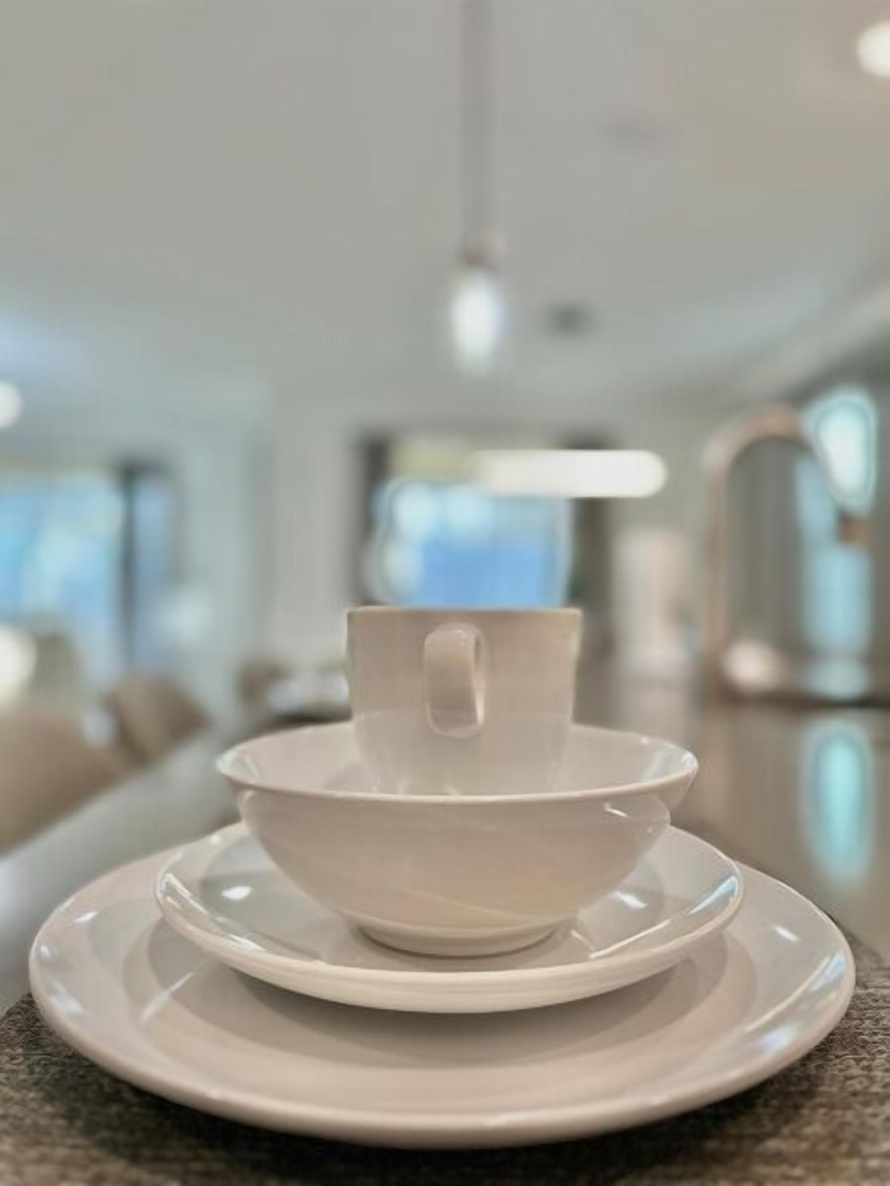 Een witte kop en schotel op een tafel in een moderne, goed verlichte kamer met een neutrale kleurenpalet.
