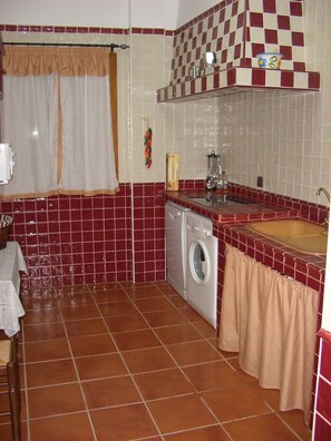 A compact kitchen with a washing machine, a sink, and a tiled backsplash. - Traditional Andalusian Mansion, Cordoba (Moriles)