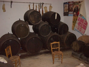 Una habitación con varios barriles de madera apilados contra la pared, una silla de madera al frente y un cartel en la pared.