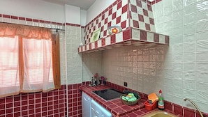 Una cocina compacta con lavadora, lavamanos y ventana con cortinas.