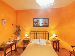 A bedroom with a bed, two bedside tables, a nightstand, a potted plant, a framed picture on the wall, and a ceiling light fixture. - Traditional Andalusian Mansion, Cordoba (Moriles)