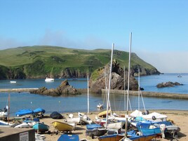 Una playa con barcos amarrados y un paisaje montañoso al fondo.