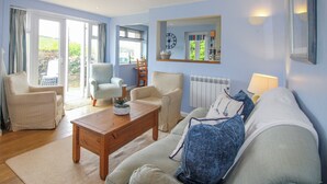 A living room with a sofa, armchairs, a coffee table, and a dining area with a chair and table. - Quay Sands, Hope Cove (Kingsbridge)