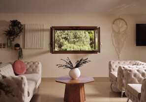 A living room with a large window, a round wooden table, and two sofas. - Casa Di Cuore Loft   Sea View & Jacuzzi Retreat (Zakynthos)