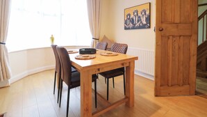 A dining area with a wooden table, black chairs, and a window with curtains.