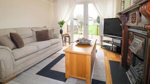 A living room with a sofa, a wooden coffee table, a television, and a fireplace.