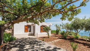 A white building with a tiled roof, a wooden door, and windows with wooden shutters. - Zingaro Anima Maris, between Scopello and Zingaro (CASTELLAMMARE DEL GOLFO)