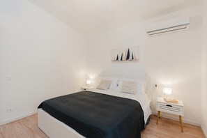 A bedroom with a bed, bedside tables, a wall-mounted air conditioner, and a painting. - Zingaro Anima Maris, between Scopello and Zingaro (CASTELLAMMARE DEL GOLFO)