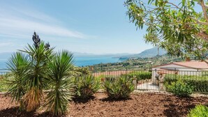 A coastal property with a fenced garden, a small building with a red roof, and a view of the sea and distant hills. - Zingaro Anima Maris, between Scopello and Zingaro (CASTELLAMMARE DEL GOLFO)