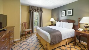 A hotel room with a bed, a dresser, a chair, two bedside lamps, and a window with curtains. - Cozy 1 bedroom condo in Williamsburg, Virginia! (Williamsburg)