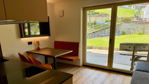 Eine moderne Küche mit Essbereich, einem an der Wand montierten Fernseher und einer Glastür zum Außenbereich.