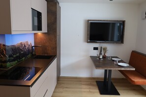 Eine moderne Küche mit eingebauter Mikrowelle, einem Esstisch mit einer Bank und einem flachbildfernseher an der Wand.