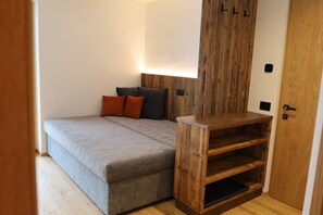 Ein Schlafzimmer mit einem Bett, einem Nachttisch aus Holz, einem Kleiderschrank und einer Wandleuchte.